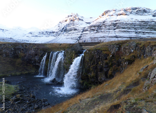 Fototapeta Naklejka Na Ścianę i Meble -  Kirkjufellsfoss waterfall and the snow capped mountain in the morning sunlight, Snaefellsness Peninsula of Iceland