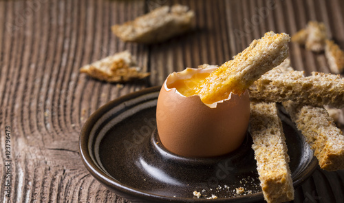 Boiled egg with crispy bread on wooden background