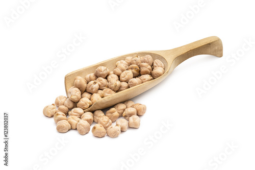 Wooden spoon with chick peas and more chickpeas next to it on a white background