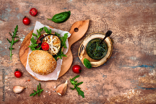 Two veggies burgers over stone vintage background. Vegan grilled eggplant, arugula, sprouts and pesto sauce burger. Veggie beet and quinoa burger. Top view, overhead, flat lay. Copy space