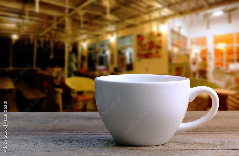 Fototapeta Biała filiżanka kawy na drewnianym stole w kawiarni rozmycie tła.
