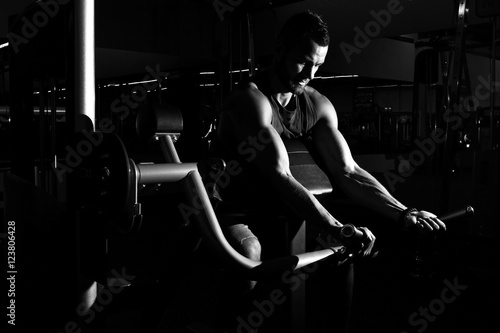 Sportive man doing exercise with barbell in the gym