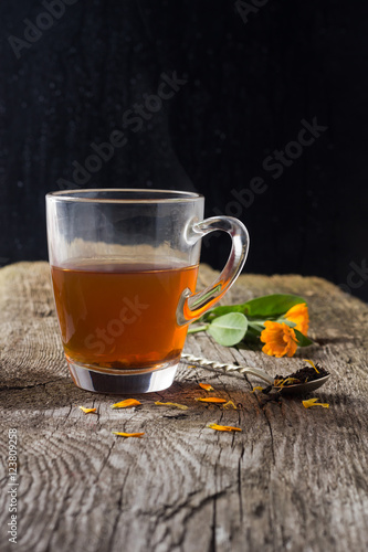 Hot cup of tea with flowers on a wooden table
