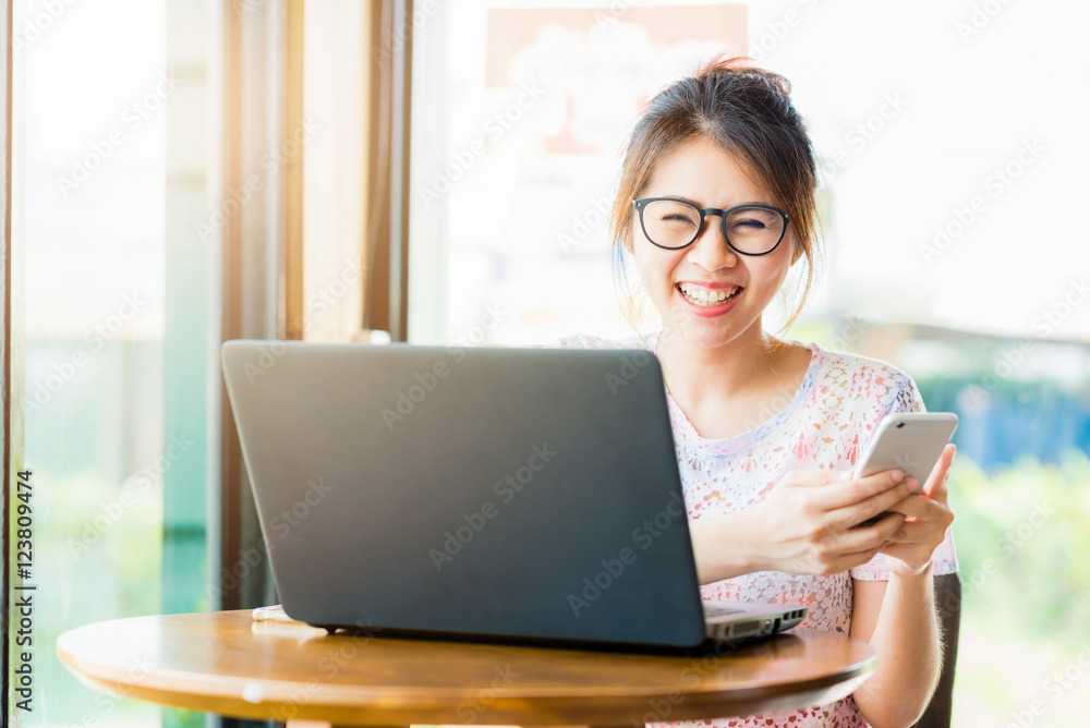 Pretty young happy asian woman laughing while holding smartphone. Pretty young happy asian woman laughing while holding smartphone.