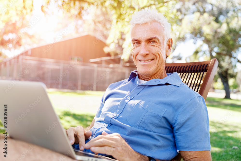 Senior man with notebook sitting in the park Senior man with notebook sitting in the park