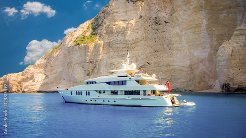 Luxury white yacht navigates into beautiful blue water near Zakynthos island. View from the top of a large white yacht at Navagio Beach.