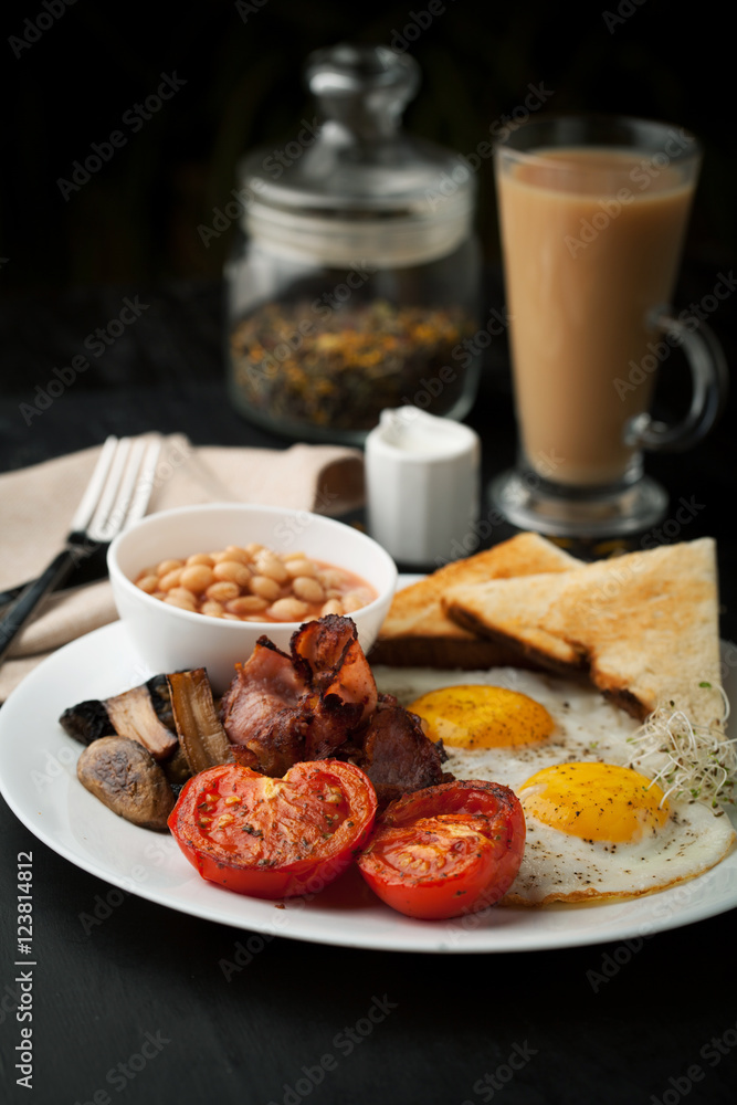 English cooked breakfast with bacon, sausage, fried egg English cooked breakfast with bacon, sausage, fried egg