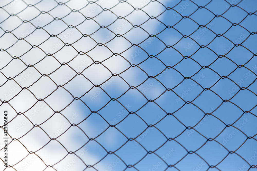 Metal mesh netting on the blue sky background and clouds Metal mesh netting on the blue sky background and clouds