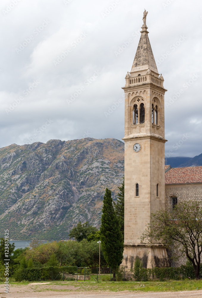 The bell tower on a background of mountains in cloudy weather in Kotor