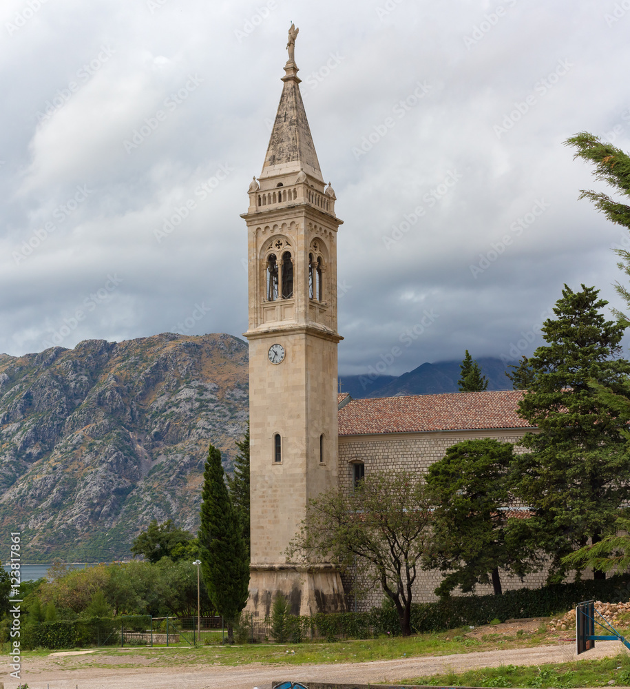 The bell tower on a background of mountains in cloudy weather in