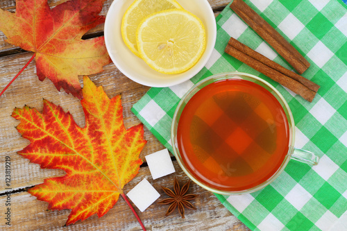Colorful autumn leaves and lemon tea on checkered cloth 
