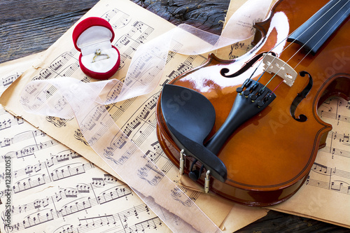 Marriage proposal with gold ring and violin on music notes