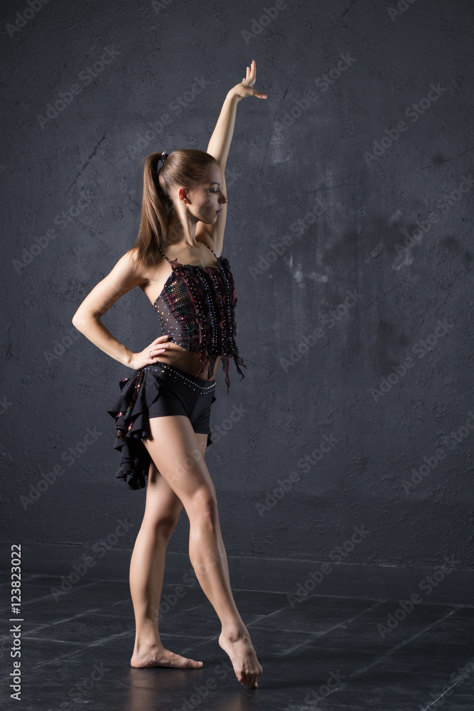 Pretty girl dancing on gray textured wall background