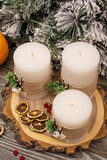 Fir branch in snow, candles by cutting the tree, berries, dry citrus on wooden background
