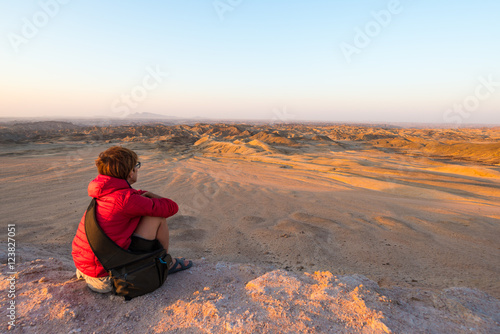 Tourist watching the stunning view of barren valley, known as "moon landscape", Namib desert, among the most important travel destination in Namibia, Africa. Panoramic view at sunset. © fabio lamanna