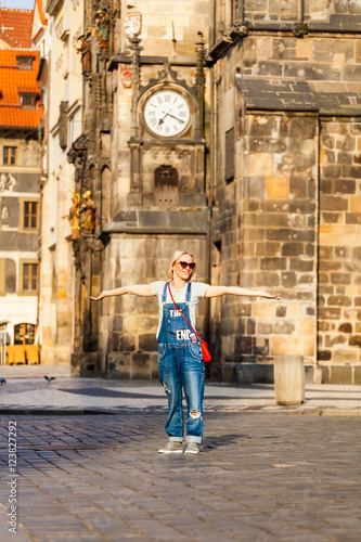 Young female traveler standing with wide open arms at the Old Town Square in Prague against the backdrop of the Old Town Hall, Czech Republic. © LALSSTOCK