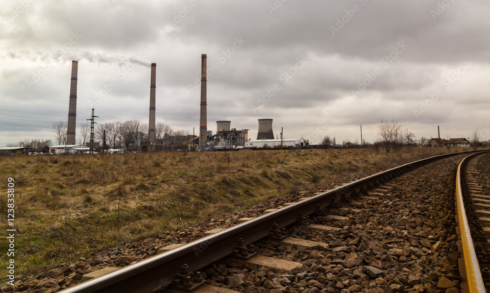 Industrial scenery with a coal power plant smoke stacks and old railroad, on a gloomy autumn day
