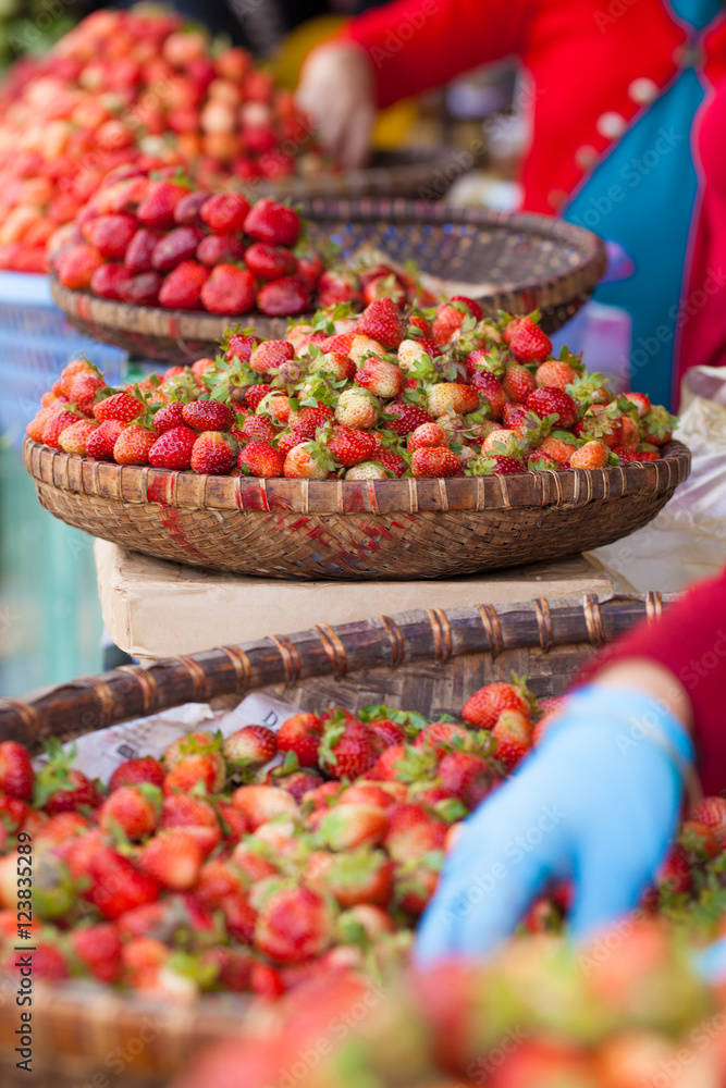 Lots of fresh red strawberry put in local style weave basket selling in fresh market, Vietnam