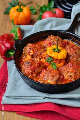 Stuffed bell pepper with minced meat and rice, and meatballs in tomato sauce in a frying pan