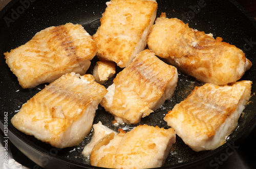 Fried cod fillet pieces on the frying pan