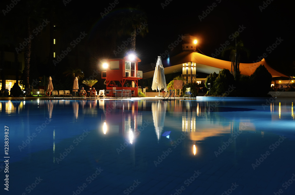 Водный ночной пейзаж. Бассейн, зона отдыха отеля при свете фонарей.