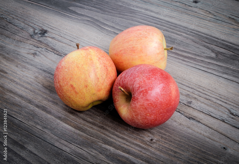 Three fresh apples on table with wooden background Three fresh apples on table with wooden background