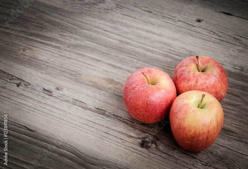 Three fresh apples on table with wooden background