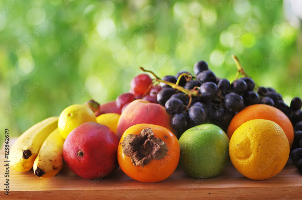 Assortment of ripe fruits on wooden table,green background Assortment of ripe fruits on wooden table,green background