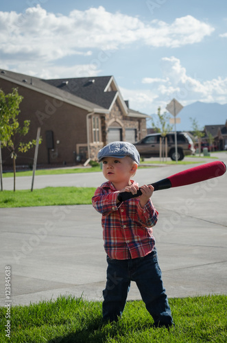 Wall Mural Toddler boy playing baseball with a white wiffle ball and red bat