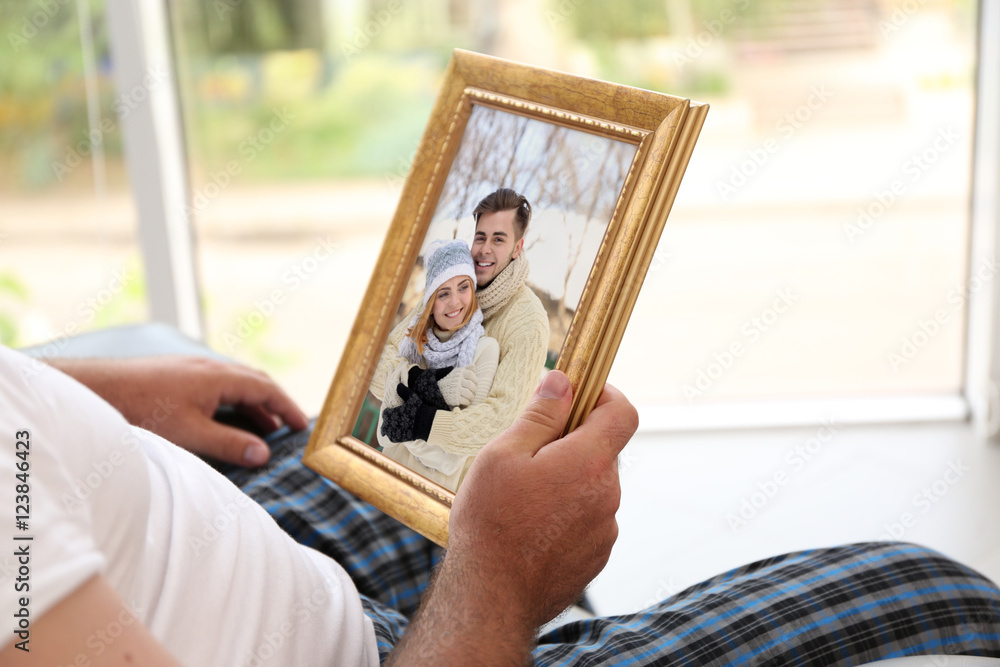 Male hands holding photo frame with picture of young couple. Happy memories concept.