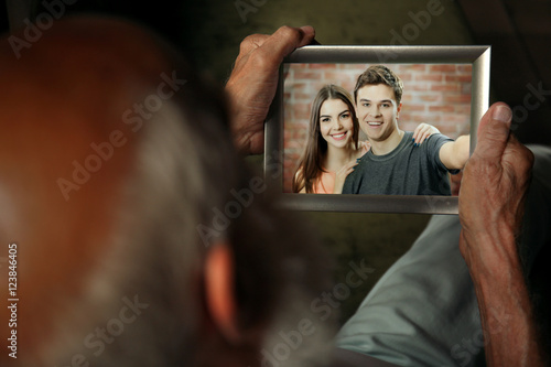Elderly man holding photo f...