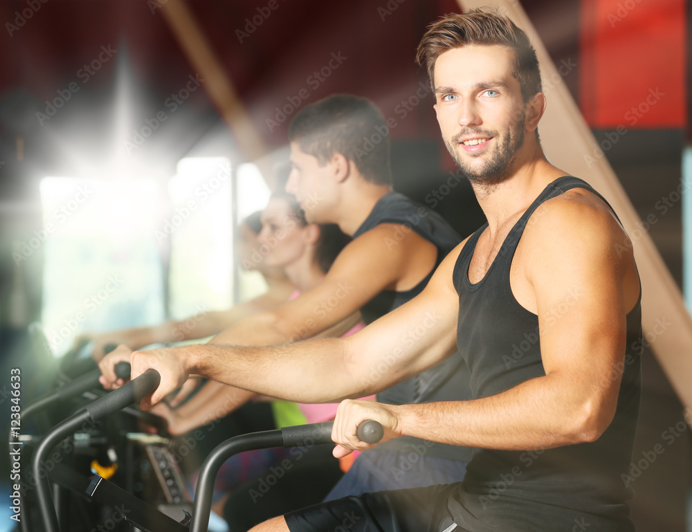 People training on exercise bike in gym People training on exercise bike in gym