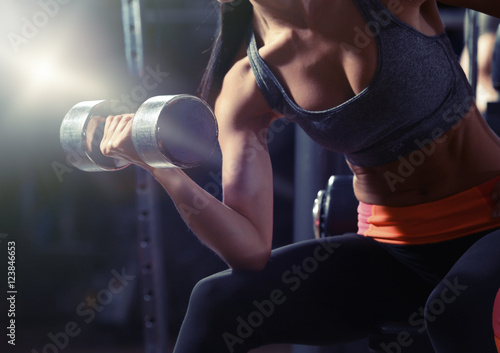 Young woman flexing muscles with dumbbell in gym © Africa Studio