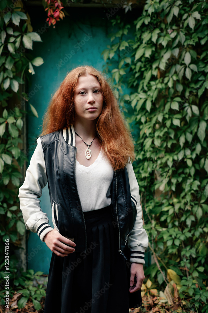 Confident young girl with red hair over green wall Confident young girl with red hair over green wall