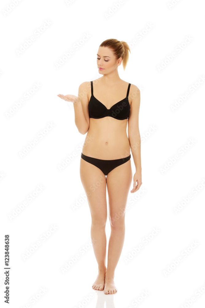 Happy woman in black lingerie presenting something on open palm Happy woman in black lingerie presenting something on open palm