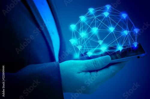 Internet of things (IOT) concept . Business woman hand holding tablet with Wifi connect icons with abstract background. blue tone image