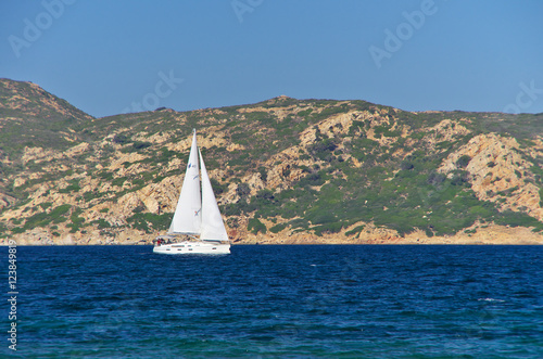 White sailboat along the granite coast of Sardinia