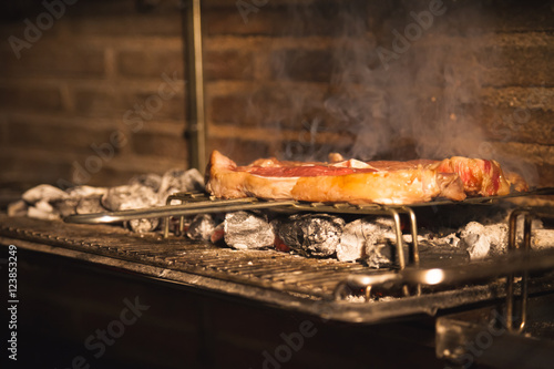 Barbecue steaks cooking on a grill with embers photo