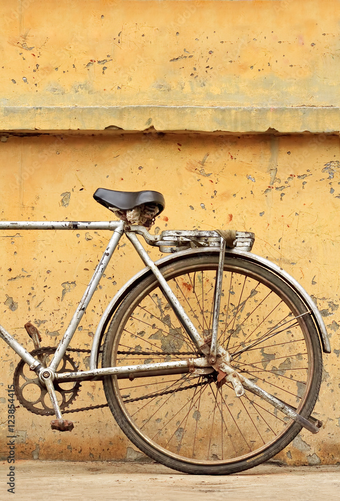 Rusty Chinese bike against weathered yellow wall