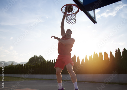 Young man jumping and making a fantastic slam dunk playing stree © FS-Stock