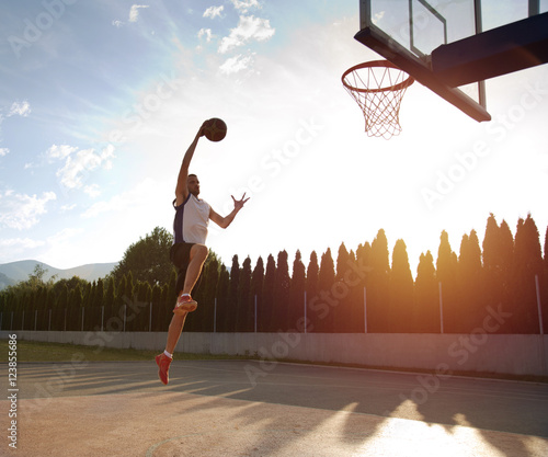 Young man jumping and making a fantastic slam dunk playing stree © FS-Stock