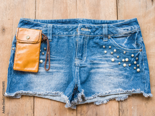 Short jean with leather bag on wood background
