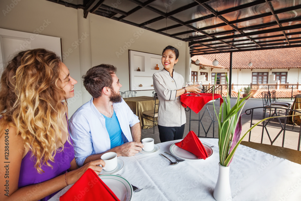 indonesian waitress serving caucasian couple in restaurant in Bali indonesian waitress serving caucasian couple in restaurant in Bali