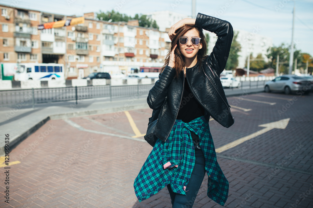 Fototapeta premium Urban fashionable girl posing in a leather jacket outdoors in the city