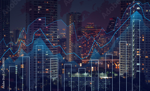 Trading graph on the cityscape at night and world map background photo