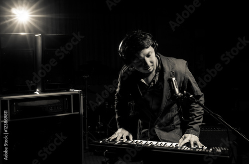 Musician playing keyboard with music instrument on dark backgrou
