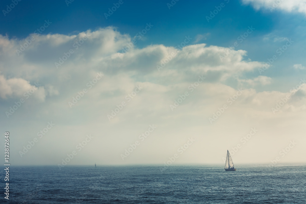 Sail boat in the foggy sea in a calm early morning