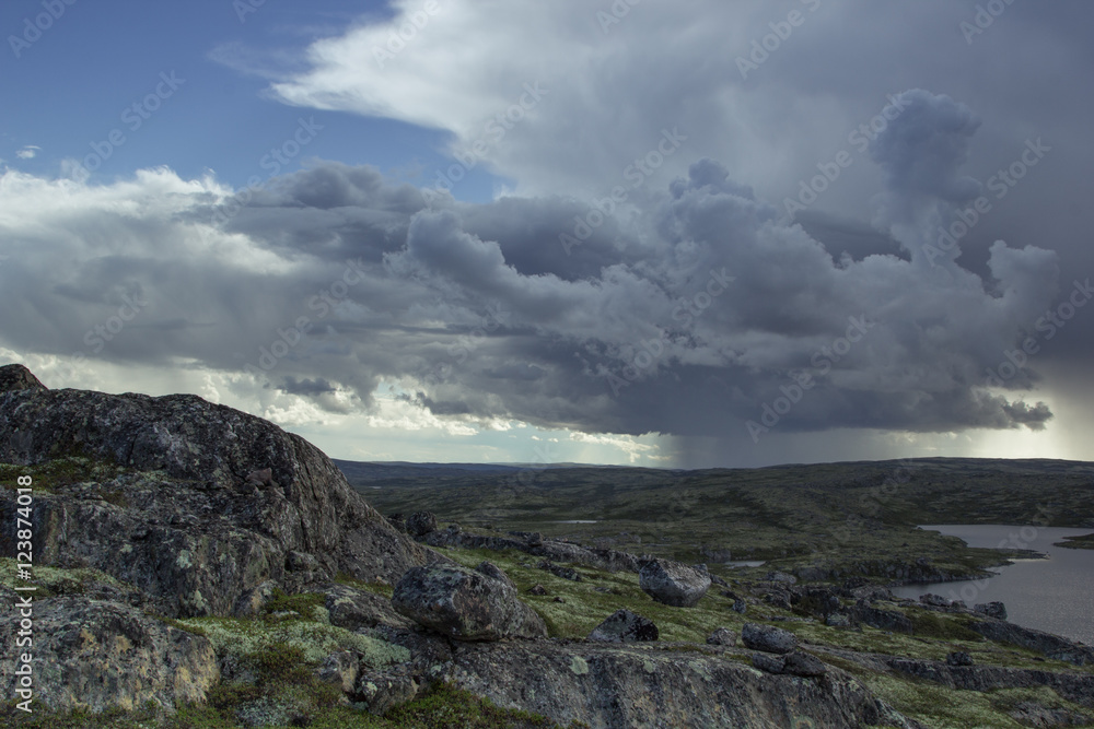 Majestic stormy cloud and sun beams over a lake in the mountains. Arctic summer, the tundra, Norway. Majestic stormy cloud and sun beams over a lake in the mountains. Arctic summer, the tundra, Norway.