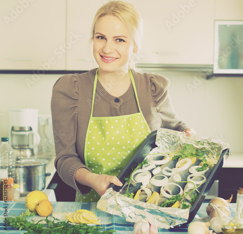 Housewife cooking fish at home photo