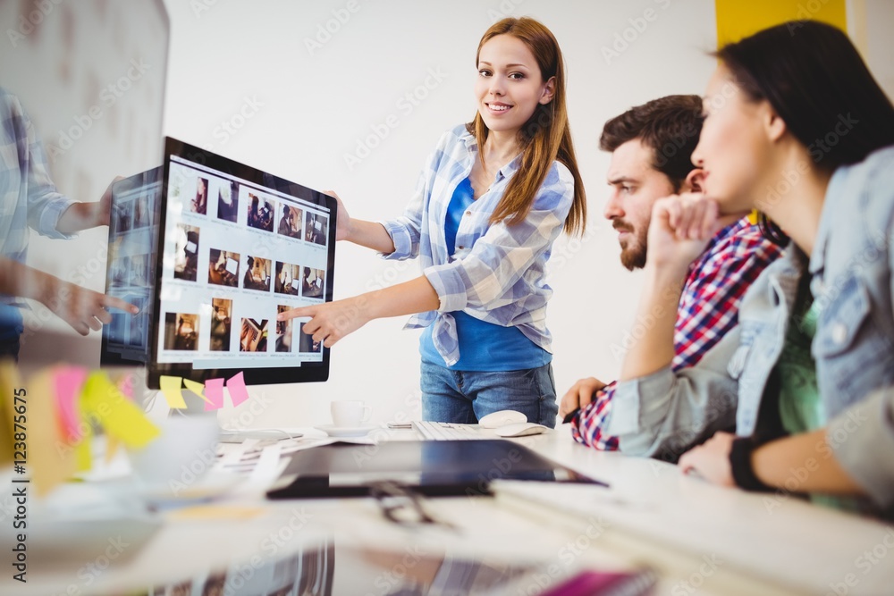 Fototapeta premium Smiling businesswoman showing computer screen to coworkers 